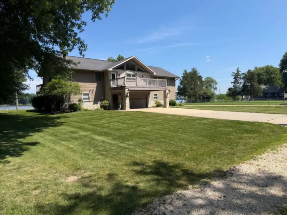 Residential lawn service with fresh mowing stripes at a riverside property in Clinton, Iowa