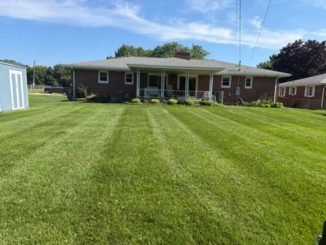 Spring cleanup and lawn mowing service with clean stripes at a brick ranch in Fulton, Illinois